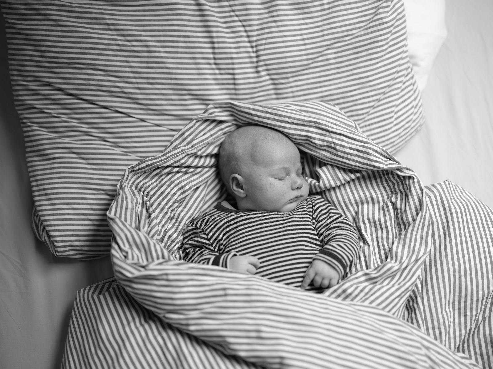 Schlafendes Baby eingewickelt in gestreifte Bettwäsche