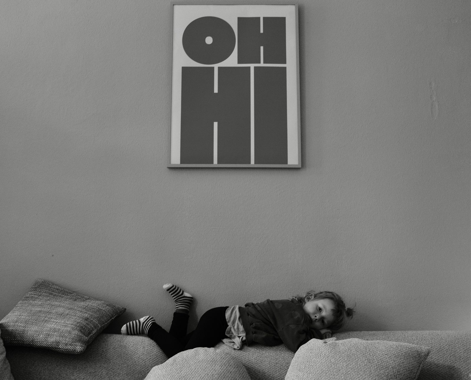 Kind liegt kopfüber lachend auf dem Sofa